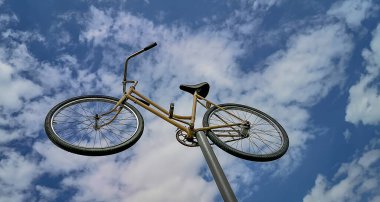 Mavi gökyüzüne karşı demir bir direkte eski bir bisiklet