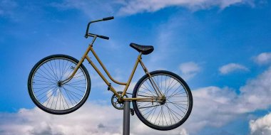 Mavi gökyüzüne karşı demir bir direkte eski bir bisiklet