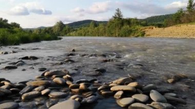 Gün batımında bir dağ nehrinin peyzaj süresi doluyor.