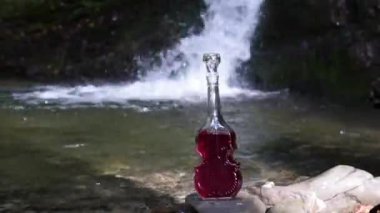 Yaz şelalesinin manzarası. Keman şeklinde bir şişe.