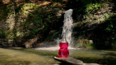 Landscape at a summer waterfall with a bottle in the form of a violin