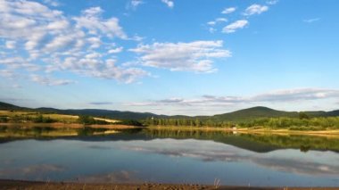 Kara ve beyaz leylek bir dağ gölünün üzerinde uçar.