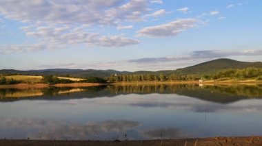 Kara ve beyaz leylek bir dağ gölünün üzerinde uçar.