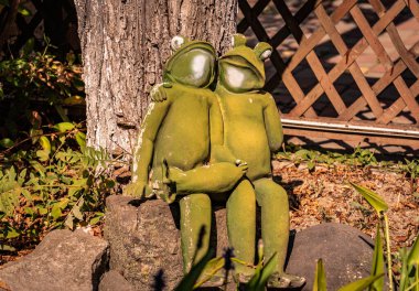 Arka bahçede kurbağaları kucaklayan heykel.