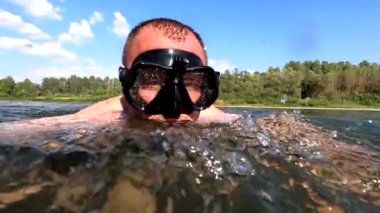A man in a mask swims in a mountain river