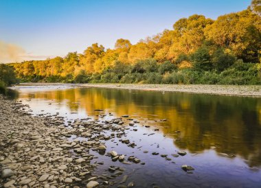 Gün batımında bir dağ nehrinin manzarası