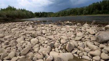 A group of people are floating on inflatable rafts in the distance along a mountain river