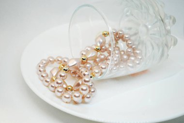 Düğün dekoru: beyaz bir tabakta bir bardakta pembe inciler dizisi