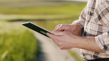 Tablet üzerinde çalışan bir adamın elleri. Sahada bekliyor. Verileri bir masaya yerleştiriyor. Çiftçi tarlasını inceliyor. 4K