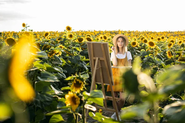 Bir kadın ayçiçeği tarlasında duruyor ve resim çiziyor. Tuval bir sehpanın üzerinde duruyor. O, kameraya bakıyor. Elinde bir fırça ve palet tutuyor..
