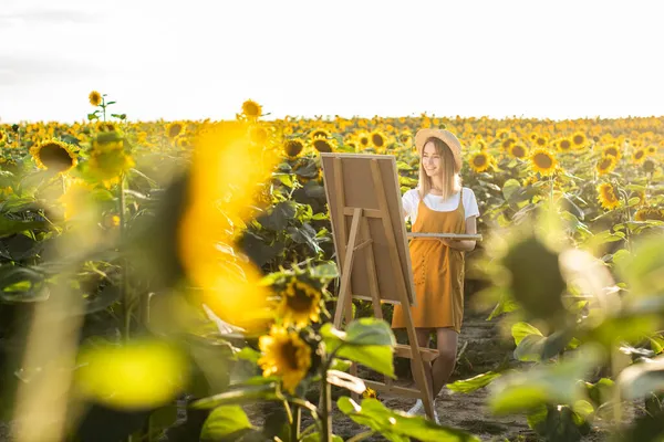 Bir kadın ayçiçeği tarlasında duruyor ve resim çiziyor. Tuval bir sehpanın üzerinde duruyor. O gülümsüyor. Güneş ışıl ışıl parlıyor. Ayçiçekleri ön planda.