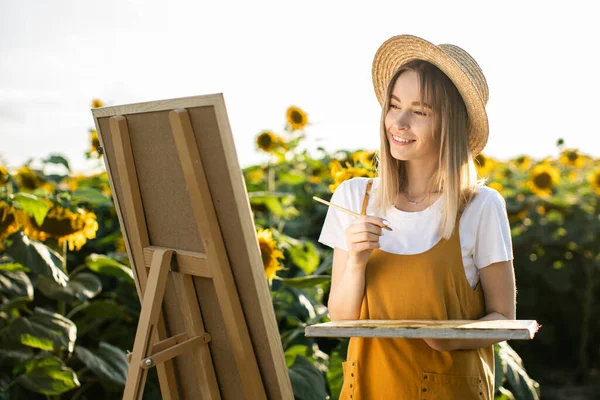Bir kadın ayçiçeği tarlasında duruyor ve resim çiziyor. Tuval bir sehpanın üzerinde duruyor. O gülümsüyor ve resme bakıyor. Elinde bir fırça ve palet tutuyor..
