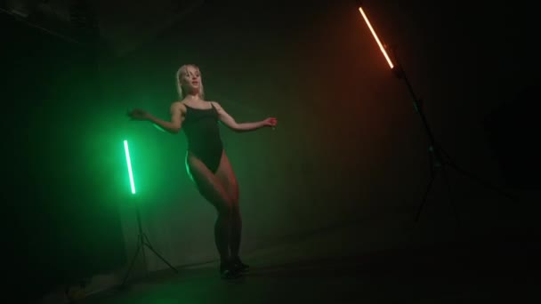 Фітнес-модель в боді-костюмі стрибає на мотузці. Кардіо-тренування. На ній сяє оранжеве і зелене світло. 4K 50 кадрів в секунду — стокове відео
