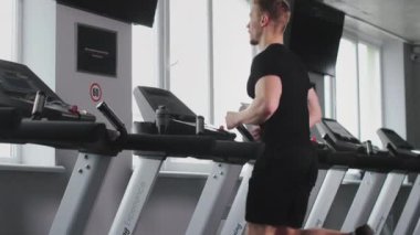 Sporcu bir koşu bandında koşuyor. O, pencereden dışarı bakıyor. Kardiyo eğitimi. 4K