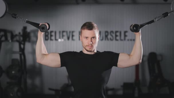 Egy sportos ember bicepszgyakorlatot végez. Komolyan a kamerába néz. Edzés az edzőteremben. 4K — Stock videók
