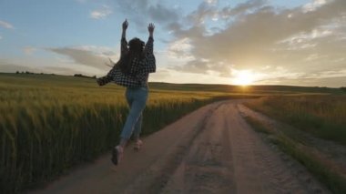 Gün batımında tarlada koşan neşeli bir kadın.