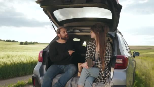 Šťastný milující pár odpočívá v kufru auta na venkově — Stock video
