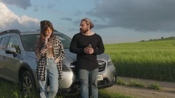 Pár stojí na venkově v blízkosti auta a pije kávu — Stock video