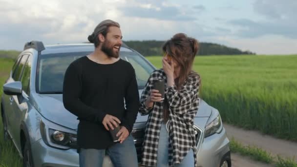 Radostný pár stojící poblíž auta mezi zeleným letním polem — Stock video
