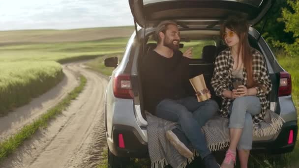 Heureux jeune couple prenant une pause sur le terrain pendant le voyage en voiture — Video