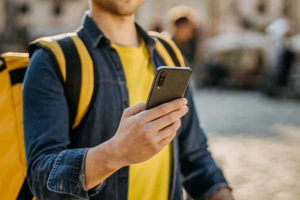 Ayakta duran ve gülümseyen bir teslimatçının portresi. Sarı bir şapka ve gözlük takıyor. Yakın çekim..