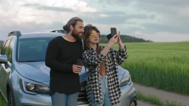 Araba yolculuğu sırasında fotoğraf çekmek için cep telefonu kullanan çift. — Stok video