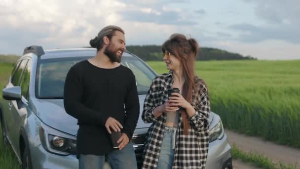 Jonge vrouw en man drinken koffie en chatten in de buurt van auto — Stockvideo