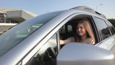 Genç kadın kameraya bakıyor ve gülümsüyor. O, açık pencereden dışarı bakıyor. Rüzgar saçlarını savuruyor. Kamera hareket ediyor. 4K