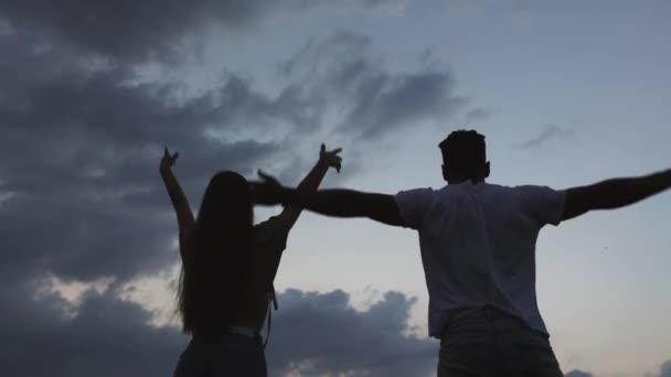 A man and a girl are standing and looking up at the sky. A plane is flying over them. They are raising their hands and rejoice. 4K — Stockvideo