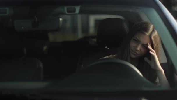 En ung kvinna sitter i sin bil i förarsätet. Hon är trött och besviken. Hon har handen på ratten. 4K — Stockvideo
