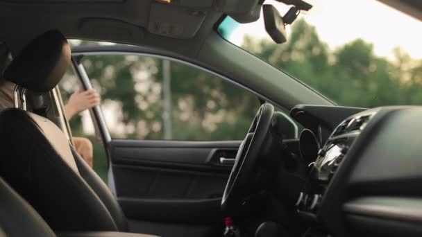 Genç bir kadın kapıyı açıyor ve sürücü koltuğunda oturuyor. Maskesini çıkarıyor ve arabayı çalıştırıyor. Yan koltuklardan ateş ediyorlar. 4K 50fps — Stok video