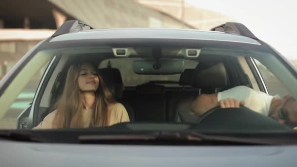A man and a woman are opening the door and getting into the car. They are putting the seat belts. They are looking at each other. 4K 50fps — Vídeos de Stock