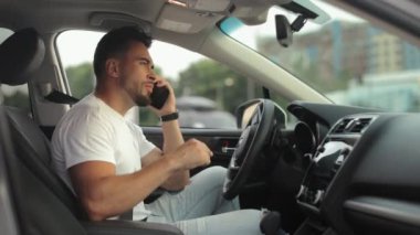 Sürücü koltuğunda bir adam oturuyor. Telefonda konuşuyor ve el sallıyor. Yan koltuklardan ateş ediyorlar. 4K 50fps
