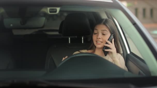 A young woman is sitting in the drivers seat. She is talking seriously on the phone. 4K 50fps — Wideo stockowe
