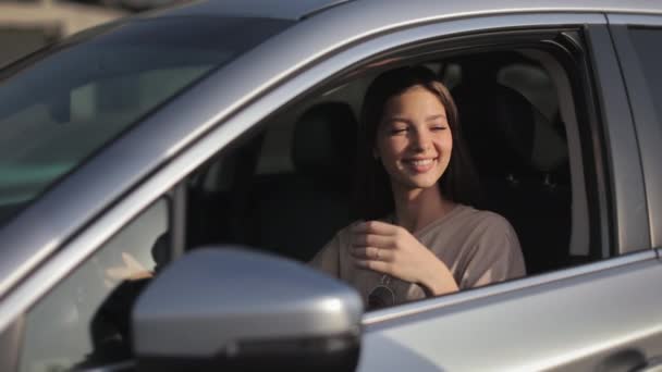 A young woman is sitting in the car in the drivers seat. The man is giving the car key through the window. She is smiling and thanks. She is looking at him. 4K — Vídeo de Stock