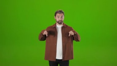 Male hipster pointing down over green background