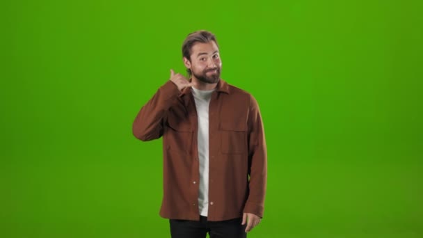 Bearded man doing phone gesture over green background — Vídeo de Stock