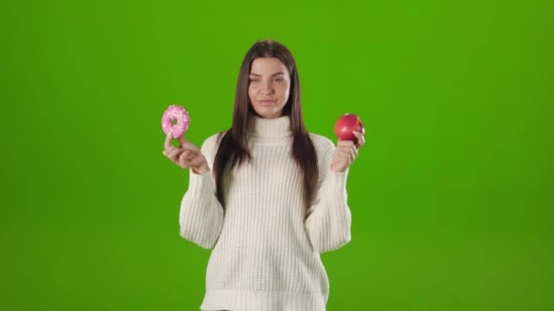 Positive woman posing in studio with apple and donut — Wideo stockowe