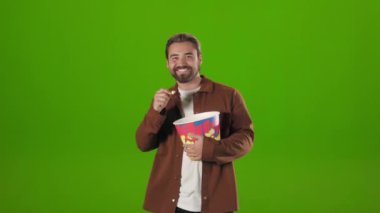 Man dancing with basket of popcorn over green background