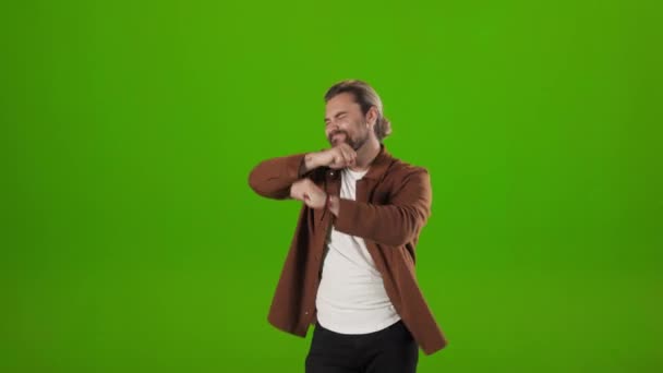 Positive man dancing happily over green studio background — стоковое видео