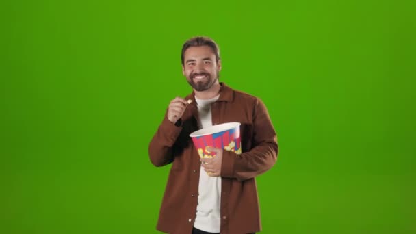 Man dancing with basket of popcorn over green background — Vídeo de stock
