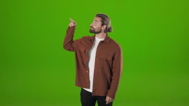 Sonriente hombre barbudo señalando con el dedo sobre fondo verde — Vídeos de Stock