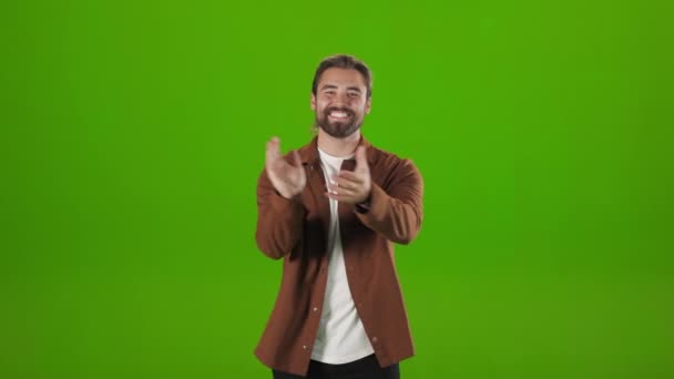 Cheerful guy applauding while standing over green background — Video Stock