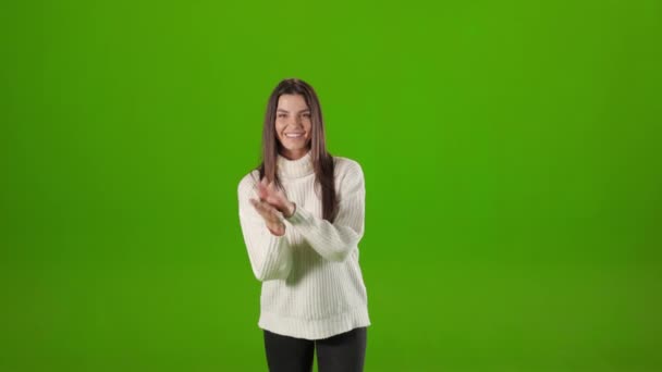 Charmant brunette klappen in handen over groene achtergrond — Stockvideo