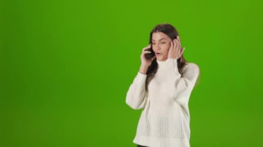 Mutlu kadın yeşil arka planda cep telefonuyla konuşuyor.