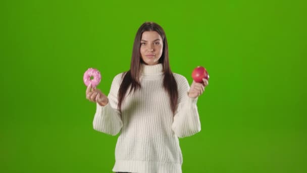 Woman making choice between apple and donut — Stock Video