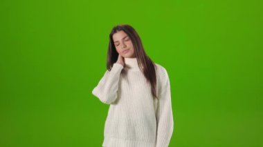 Woman suffering from pain in neck over green background
