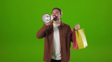 Man using megaphone and holding shopping bags in studio