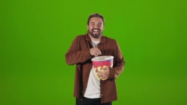 Guy with popcorn smiling cheerfully while watching comedy