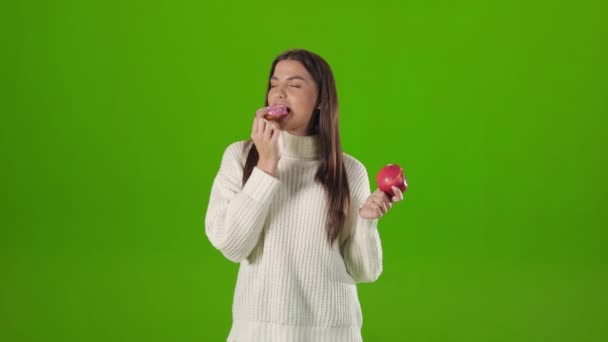 Mulher feliz escolhendo donut doce contra maçã fresca — Vídeo de Stock